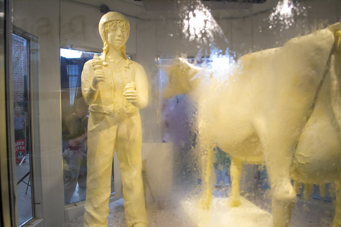 Butter Girl smiling while holding ice cream next to the 2026 Butter Cow.